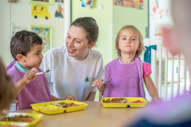 Aide ADMR qui aide des enfants à manger à la crèche